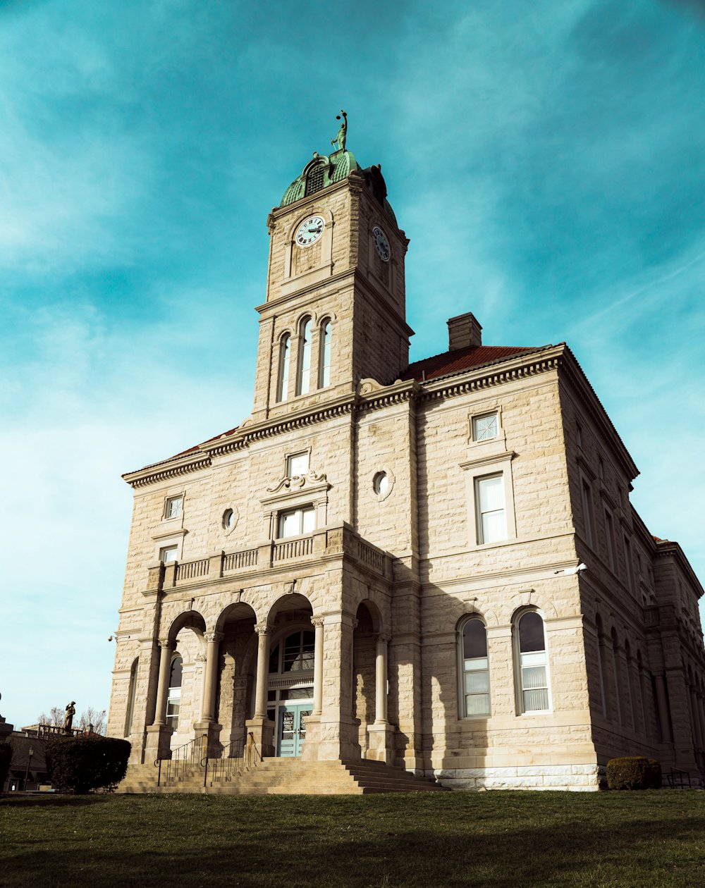 A stone civic building with a clock tower set against a blue sky.