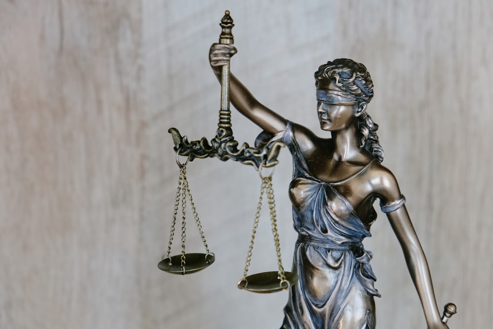A bronze statue of Lady Justice holding balanced scales, a symbol of fairness under the law.