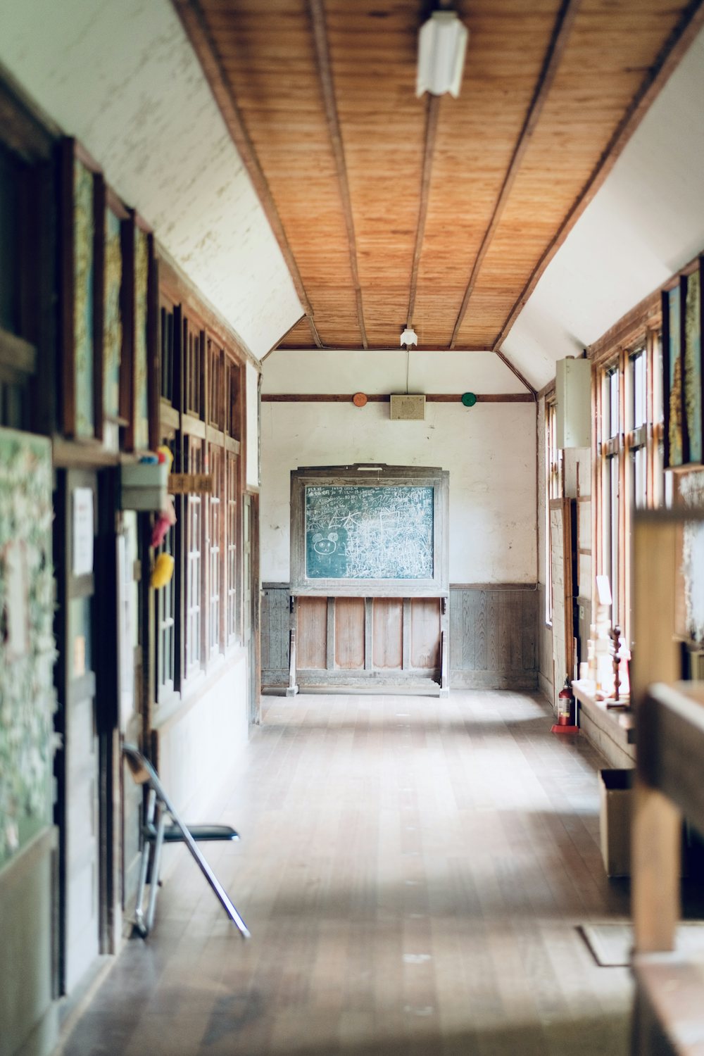 A bright, empty school hallway lined with wooden walls and tall windows.