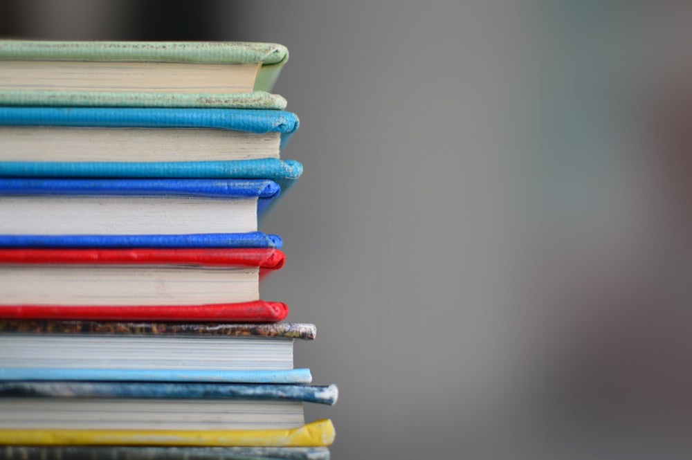 A stack of colorful notebooks and workbooks viewed from the side.