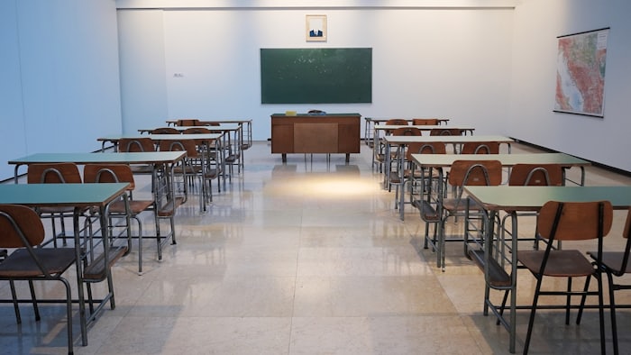An empty classroom with rows of desks facing a chalkboard.